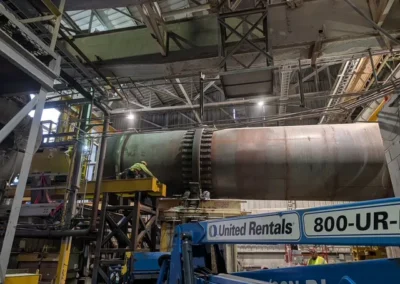 Technicians performing maintenance work on large industrial equipment using lifting machinery
